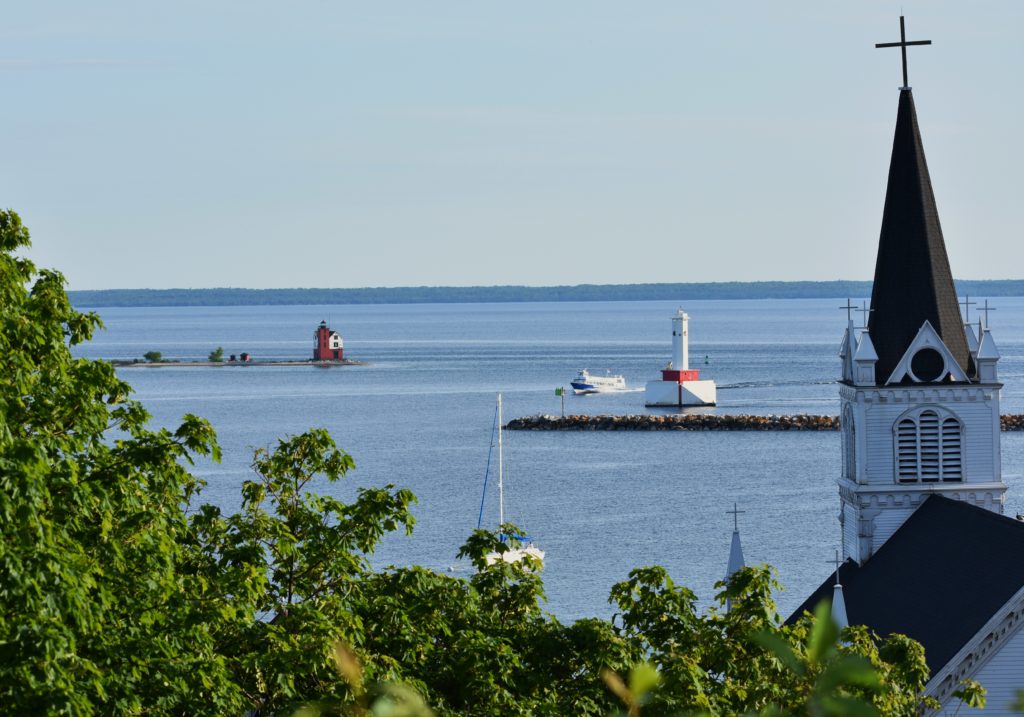Creating Your Affordable Vacation. Two lighthouses on the straits of Mackinac with church steeple in view.