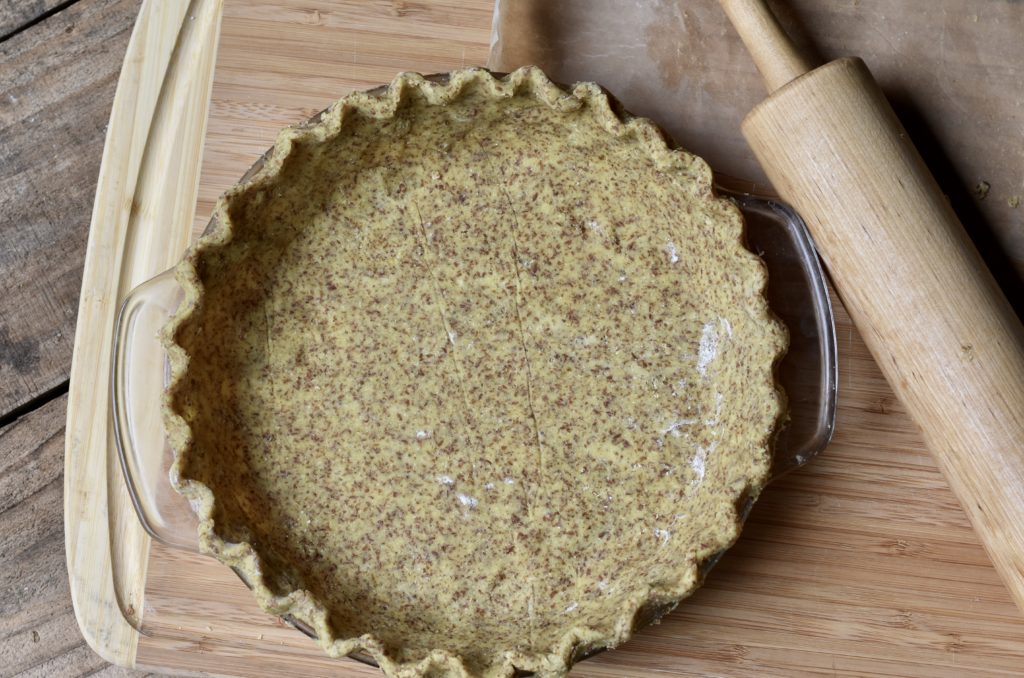 Grain free pie crust on a table next to a rollin pin.