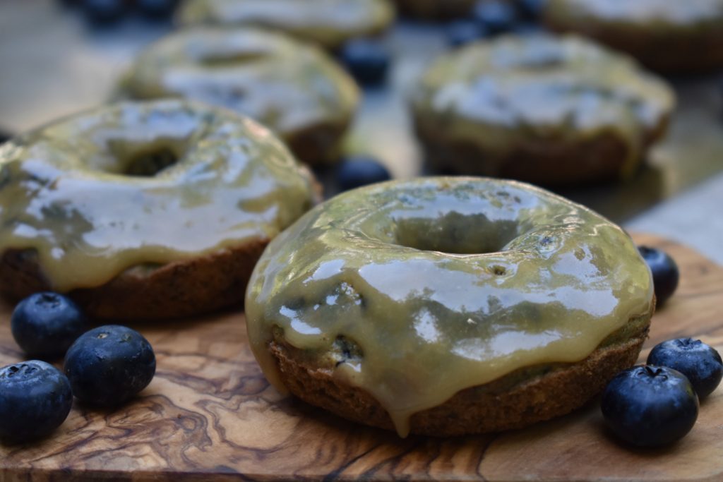Grain Free Blueberry Doughnuts with maple glaze on a cutting board.