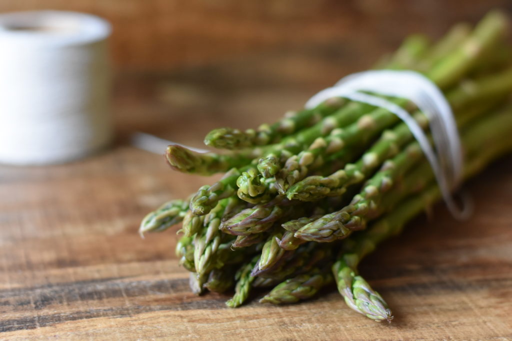 Superfoods Our Body Loves. Asparagus tied with string on a wooden table.