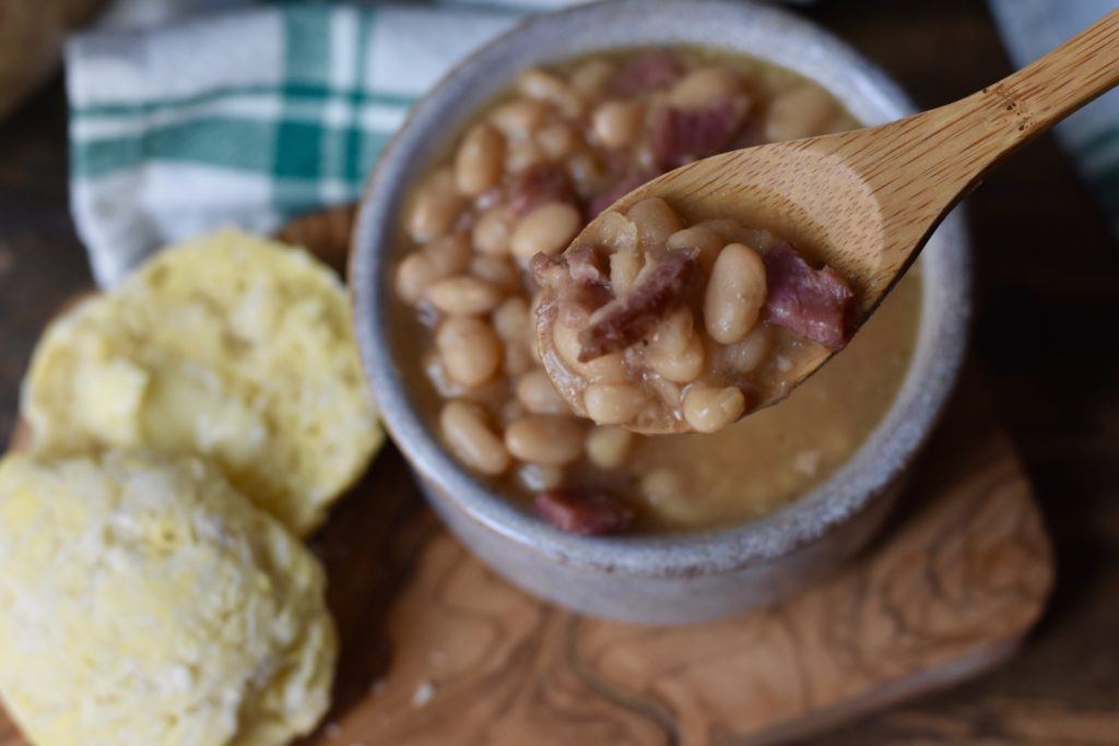 Classic Bean and Ham Soup.  A spoonful of soup with a grain free roll in the background.
