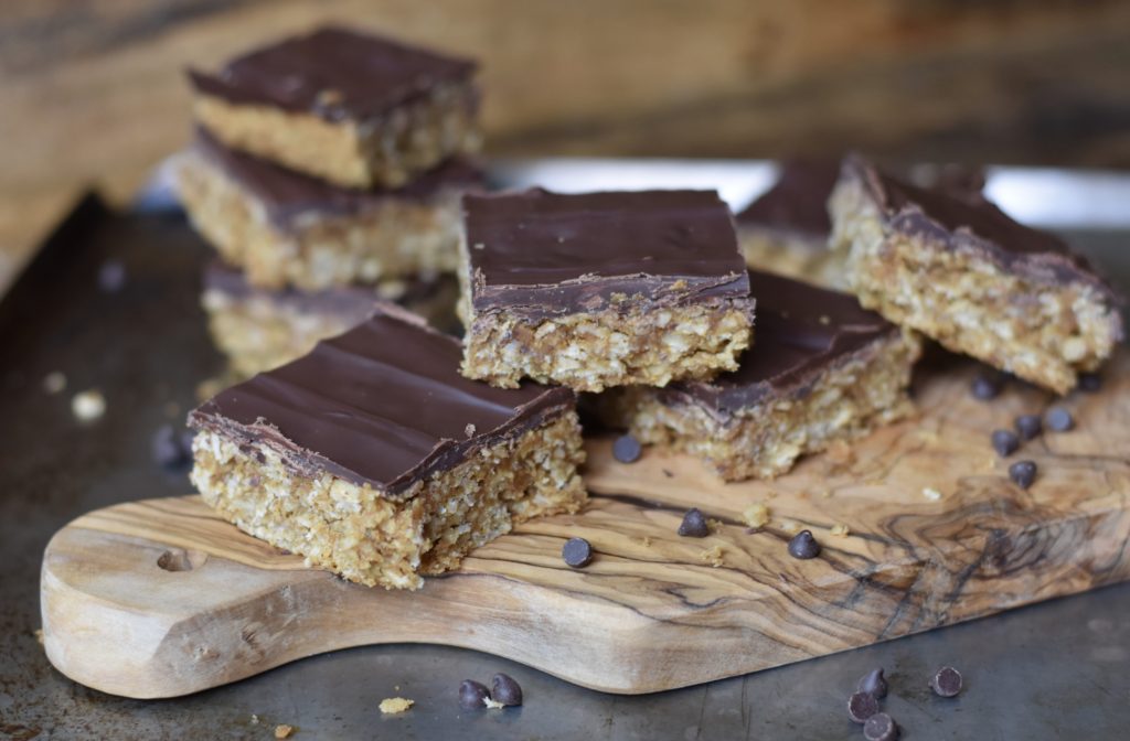 Gluten free oatmeal peanut butter chewy bars on a small cutting board.