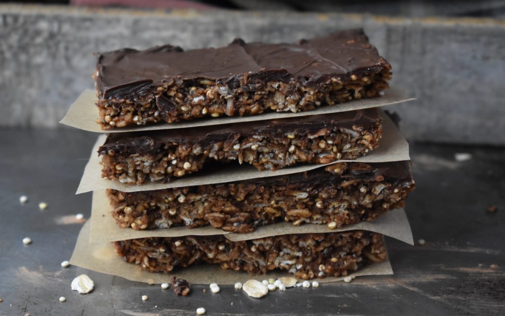Gluten Free Chocolate Mint Granola Bars. A stack of four granola bars with parchment paper between the bars.