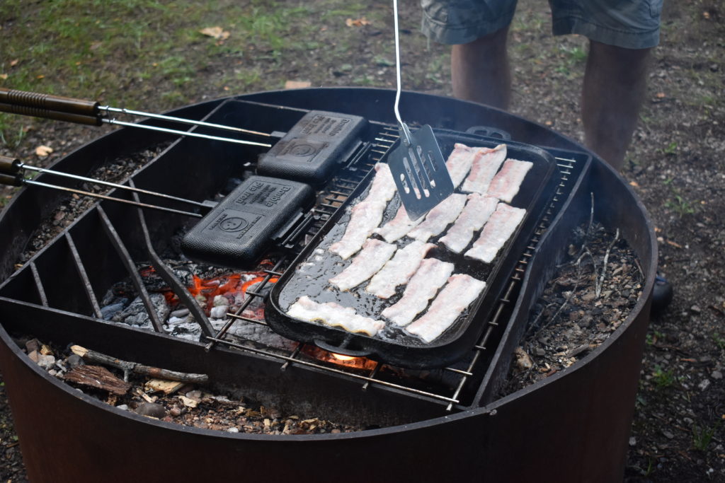 Healthy Meal Ideas for Camping Trips.  Pie irons and bacon cooking over a campfire.