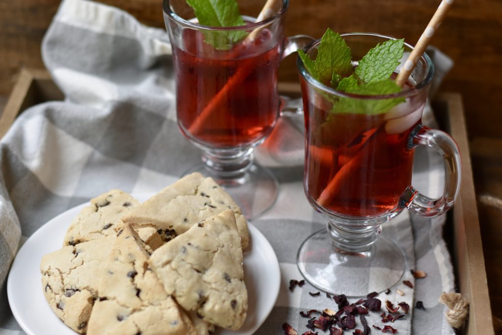 7 health benefits of hibiscus tea.  Two glasses of hibiscus tea with a plate of scones.