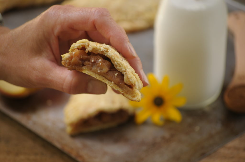 Grain Free Cinnamon Apple Hand Pies.  A person holding 1/2 a hand pie.