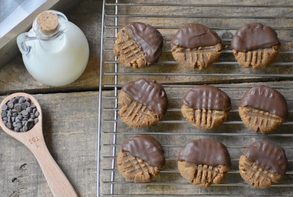 Grain Free Peanut Butter Cookies cooling on a wire rack with a jug of dairy free milk beside it.