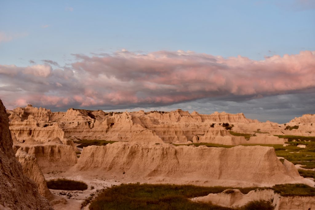 Visit Badlands National Park.  Rocks and clouds reflecting the sunrise.