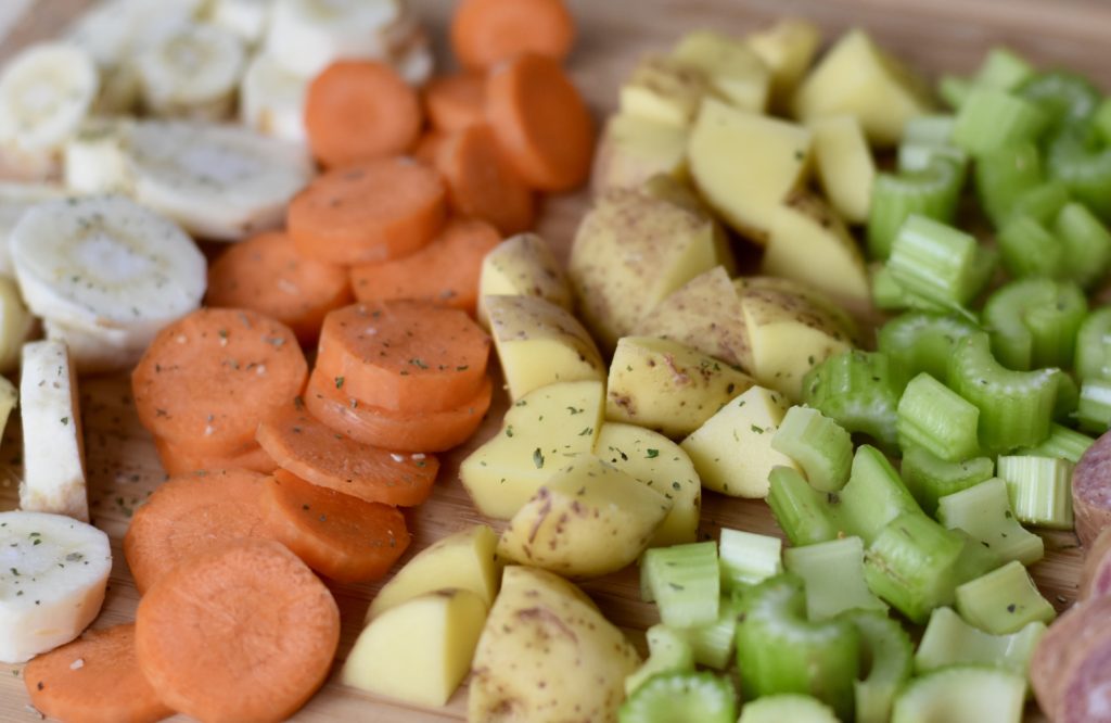 Eat the Rainbow in Vegetables.  Parsnips, carrots, potatoes and celery on a cutting board.