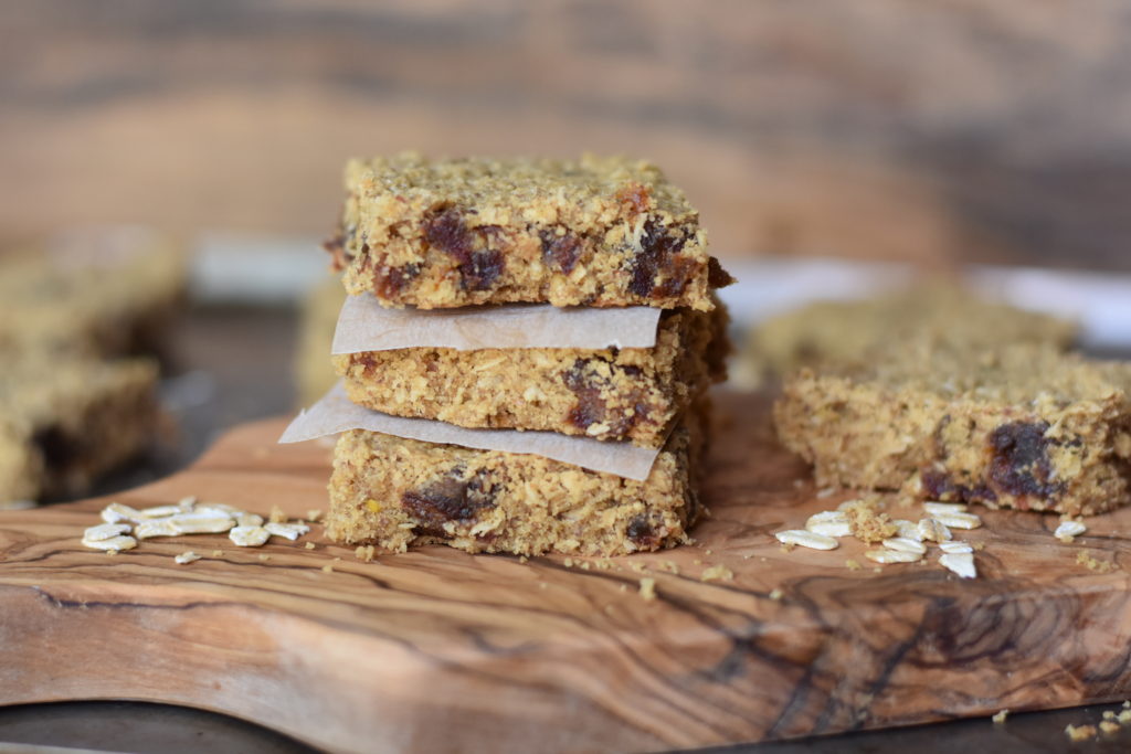 Oatmeal Coconut Date Bars stacked up on a cutting board.