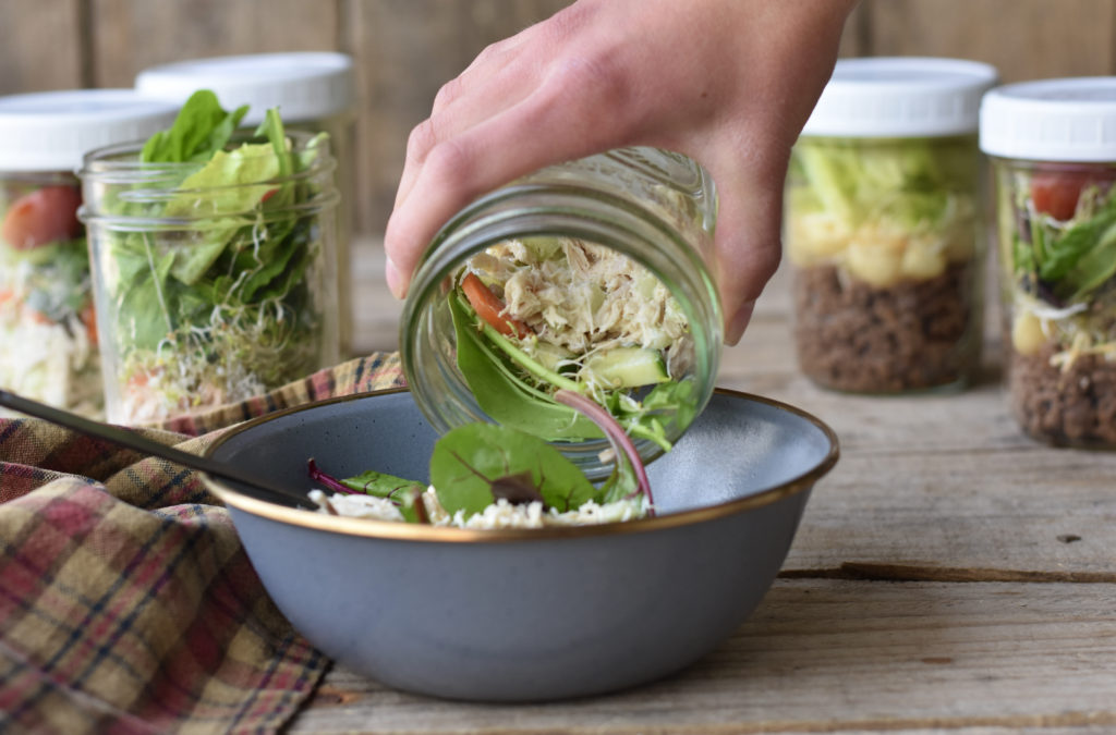 Paleo Jar Salads with chicken salad being poured into a bowl.