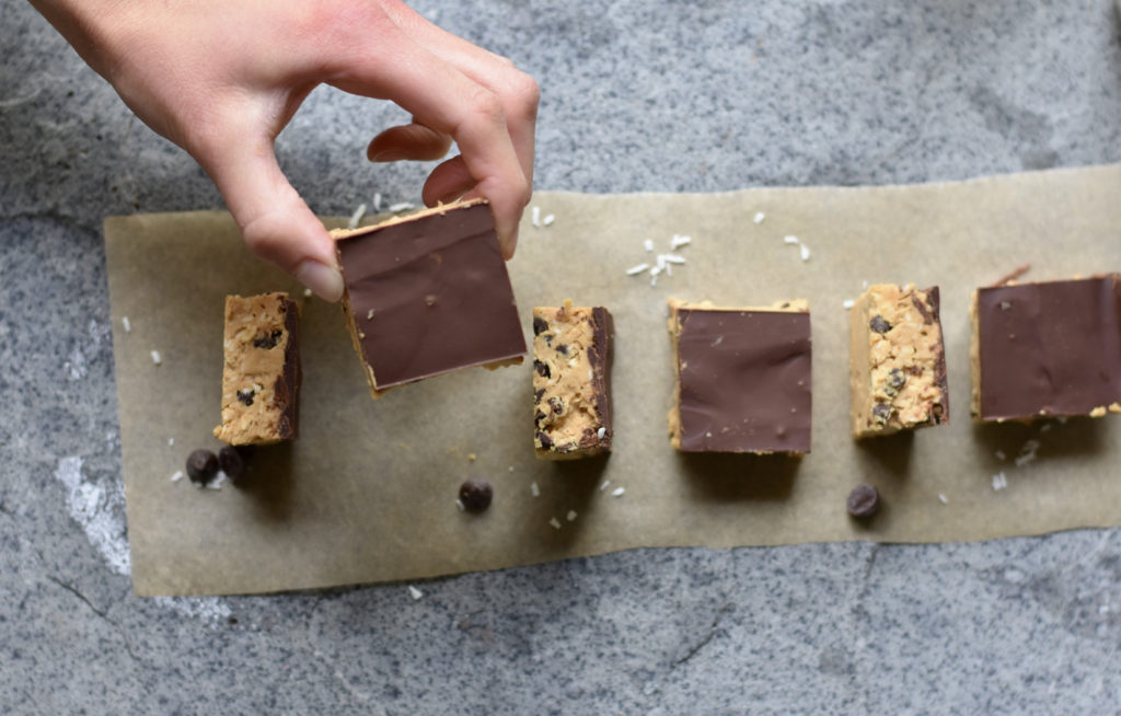 A person taking a Chocolate Chip Cookie Dough Bars Grain Free.