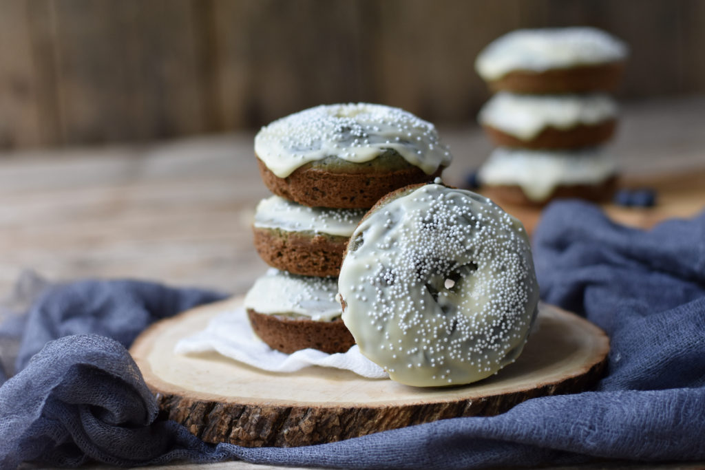 A pile of grain free blueberry doughnuts with white chocolate topping.
