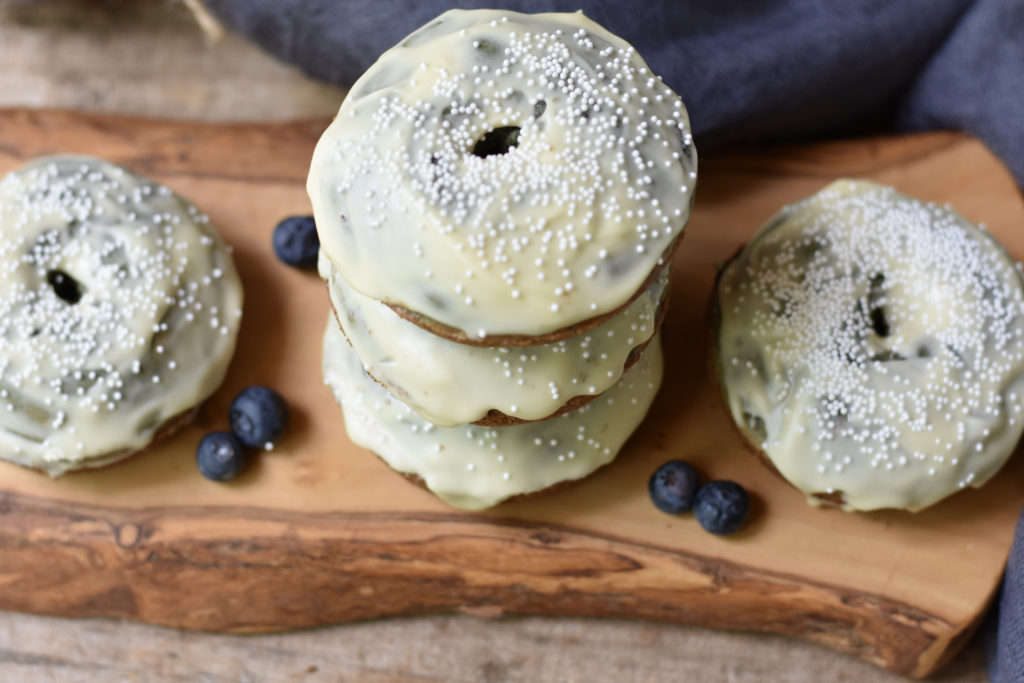 Two stacks of grain free blueberry doughnuts with white chocolate.