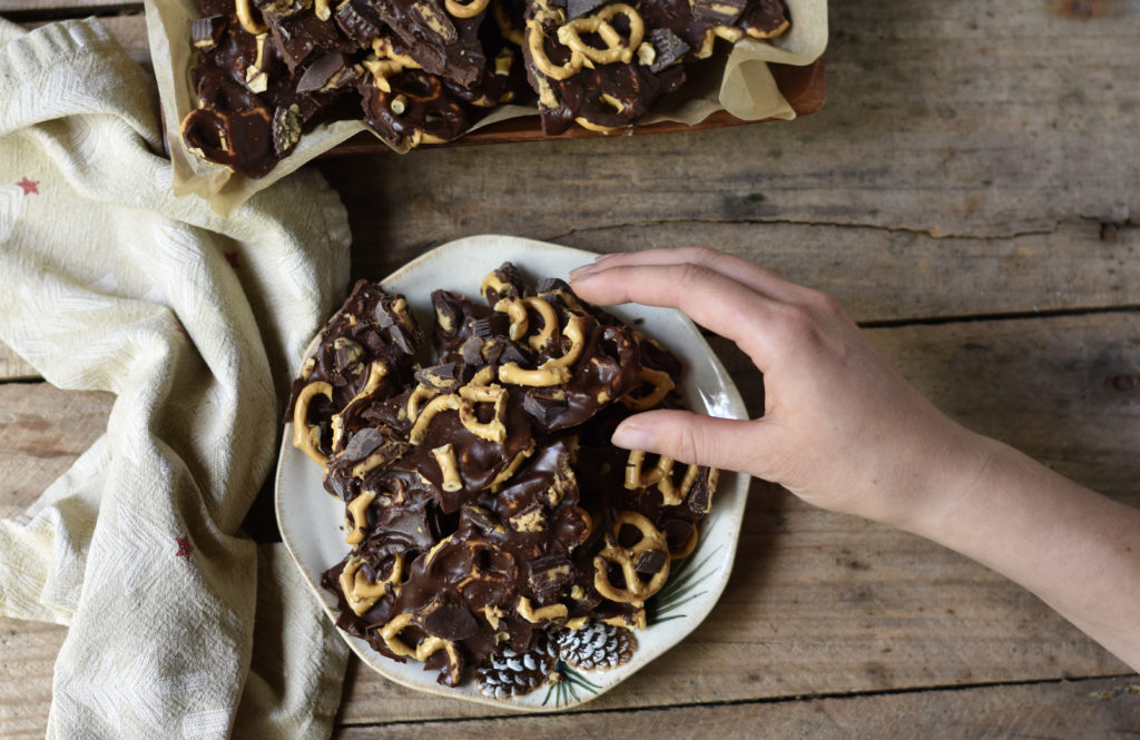 A person reaching in to take a piece of How to Make Chocolate Peanut Butter Grain Free Pretzel Bark.