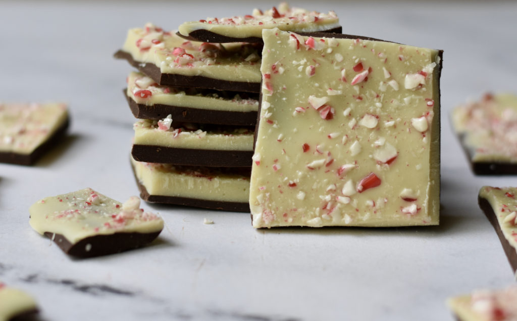 Gluten free white chocolate peppermint bark stacked in square space.
