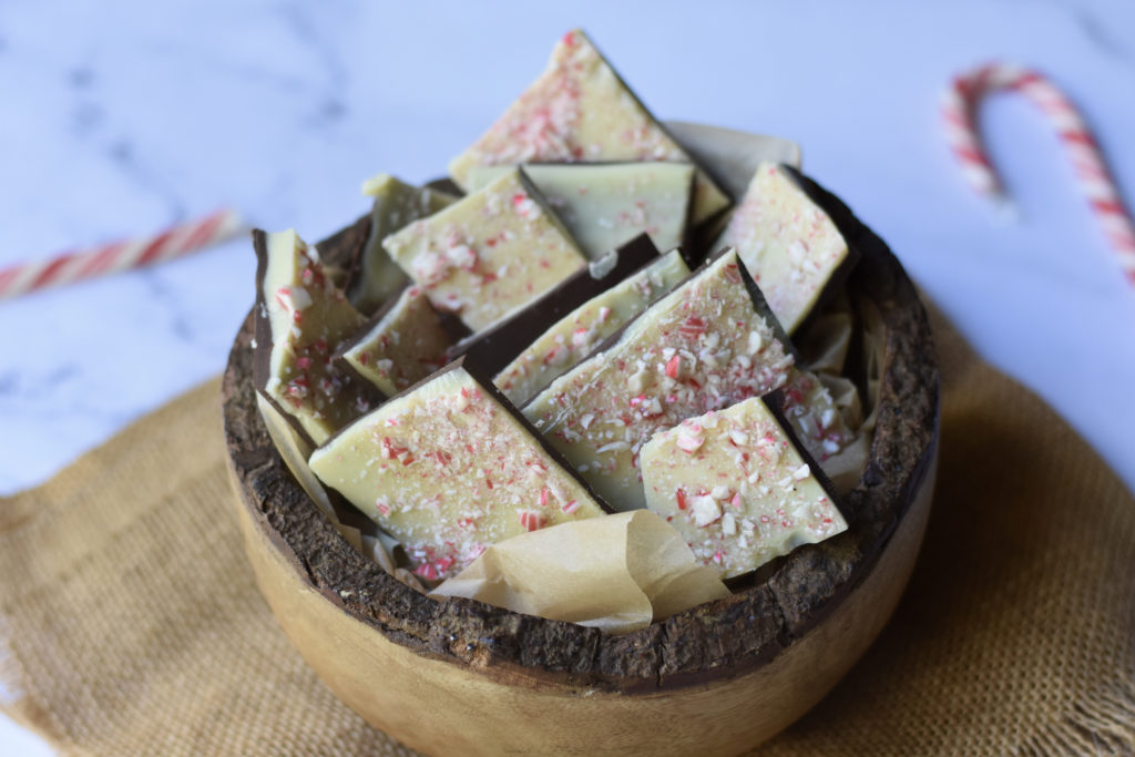 Gluten free white chocolate peppermint bark in a bowl with peppermint candy canes beside it.