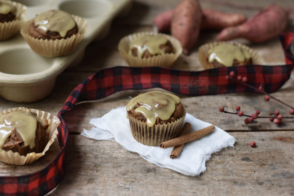 Grain free gingerbread muffins with cinnamon sticks laying beside them.