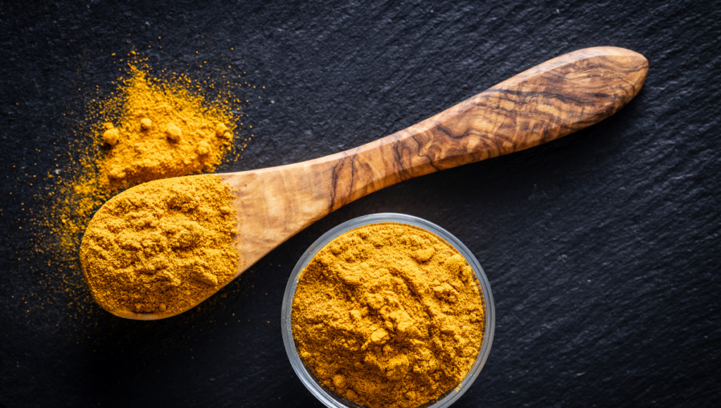 Ground turmeric on a wooden spoon, the perfect way to reduce inflammation.