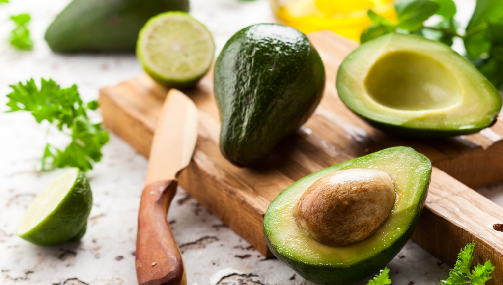 Eat avocados for weight control and a fiber rich diet.  A whole avocado and one split in half on a cutting board.