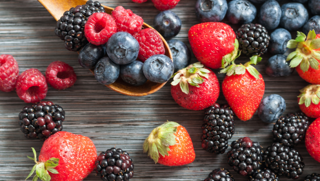 Improve your health with nutritious berries.  A spoon with blueberries, raspberries and blackberries on it.