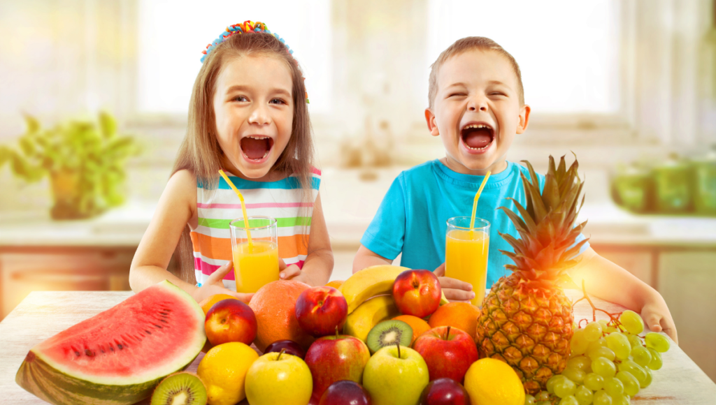 Cultivating health conscious kids with a boy and girl smiling in front of a glass of juice and fruit.
