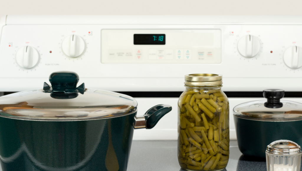 Two pots and a jar of green beans on the kitchen stovetop.